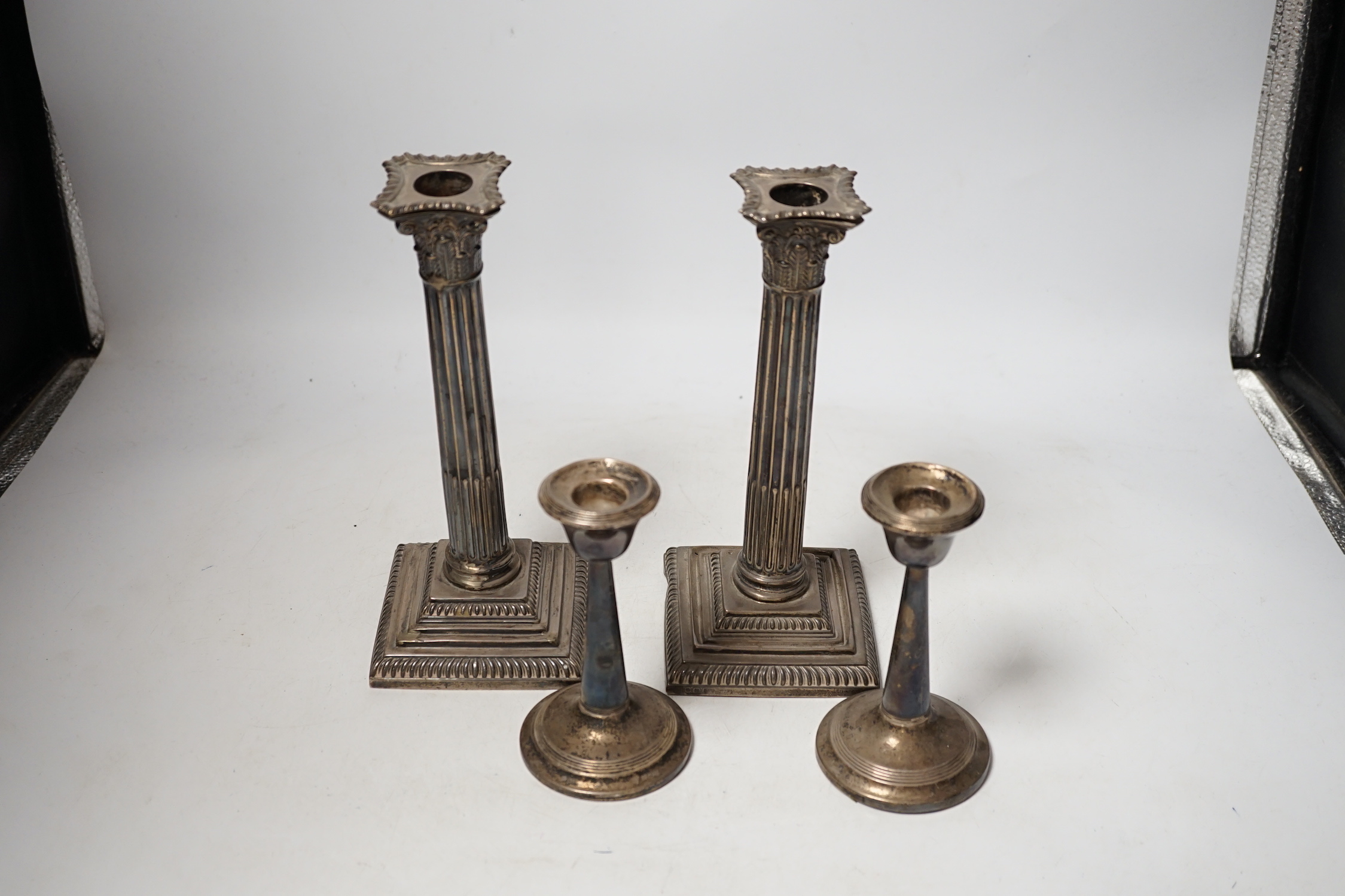 A pair of late Victorian silver Corinthian column candlesticks, Hawksworth, Eyre & Co, Sheffield 1896, 22.5cm, weighted (a.f.), and a smaller pair of silver mounted candlesticks.